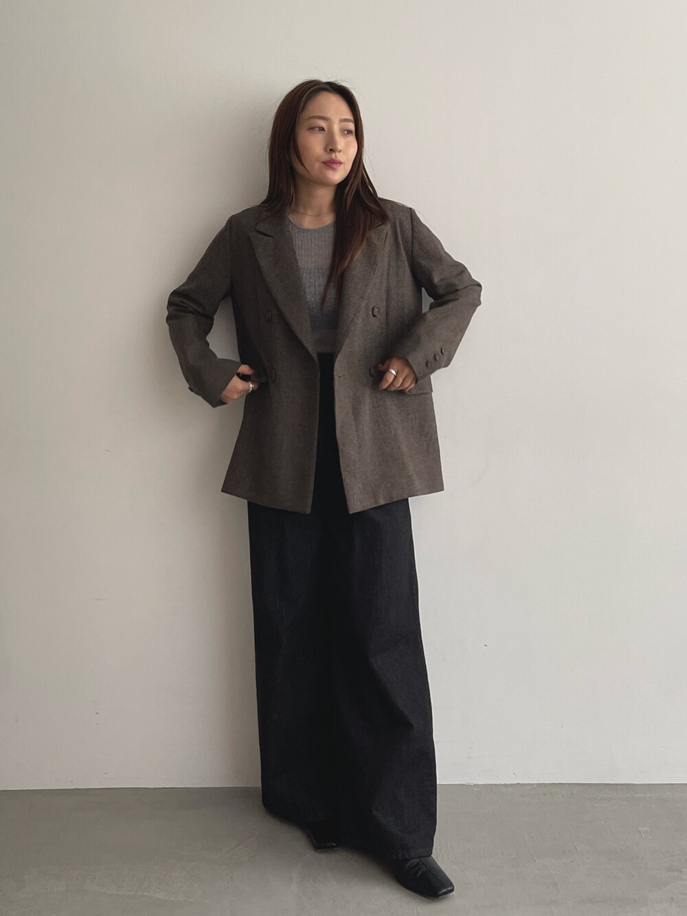 ブラック系のデニムパンツ、グレー系のニット/セーター、ブラウン系のテーラードジャケットを着用したレディースの夏コーディネートの2枚目の写真