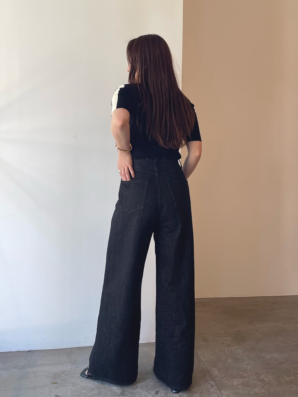 ブラック系のサンダル、ブラック系のニット/セーター、ブラック系のデニムパンツを着用したレディースの夏コーディネートの5枚目の写真
