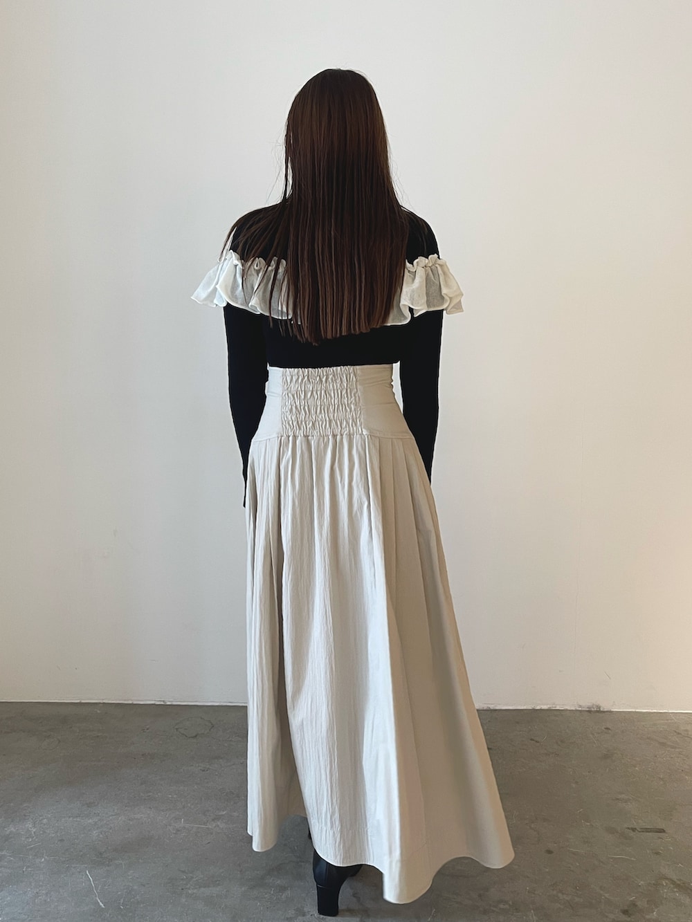 ブラック系のブーツ、ホワイト系のスカート、ブラック系のニット/セーターを着用したレディースの秋コーディネートの6枚目の写真