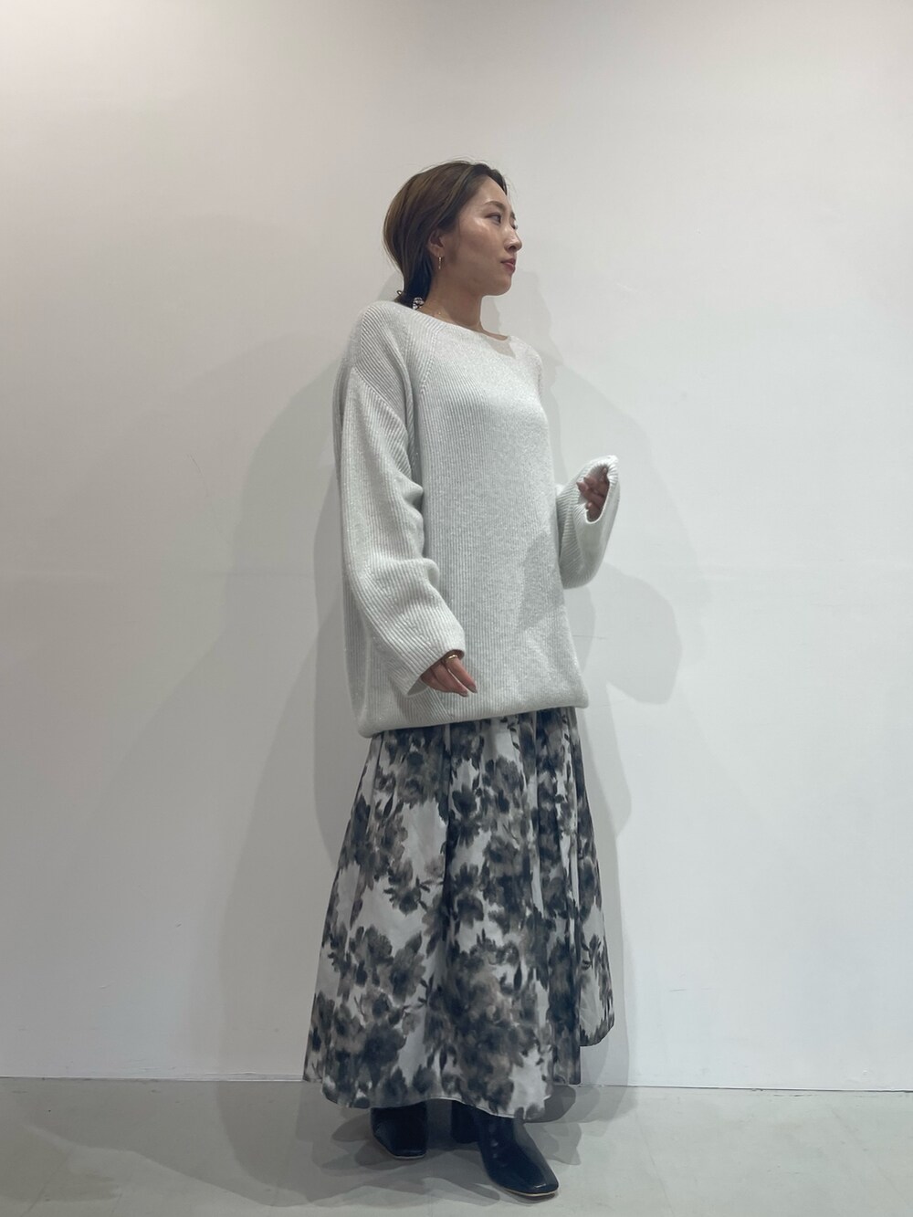 ブラック系のスカート、ブラック系のブーツ、ホワイト系のニット/セーターを着用したレディースの夏コーディネートの2枚目の写真