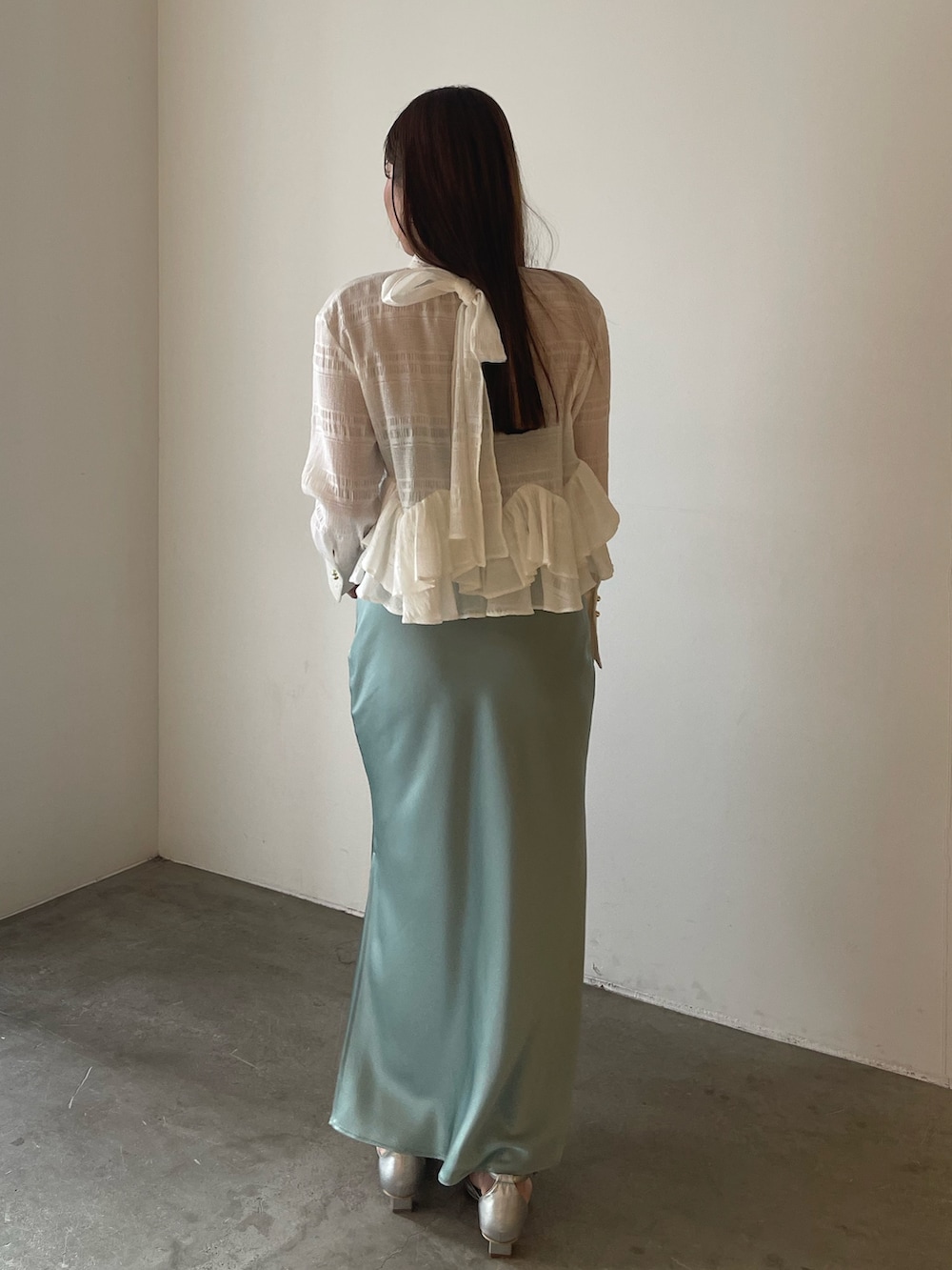 シルバー系のパンプス、ホワイト系のシャツ/ブラウス、グリーン系のスカートを着用したレディースの冬コーディネートの5枚目の写真