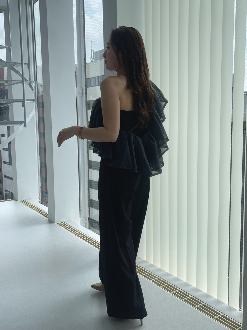 ゴールド系のパンプス、ブラック系のパンツドレスを着用したレディースの夏コーディネートの5枚目の写真