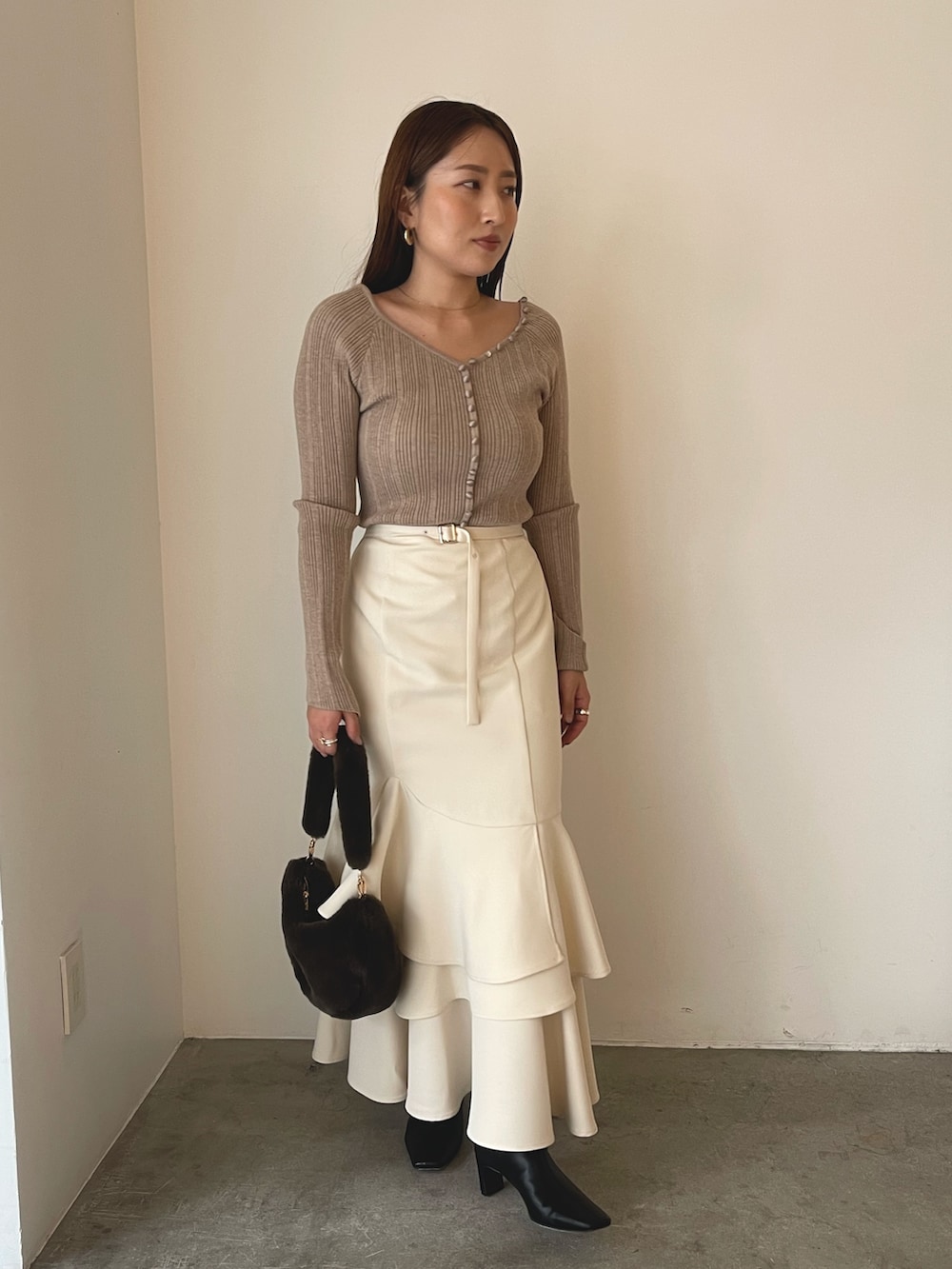 ブラウン系のショルダーバッグ、ブラック系のブーツ、ベージュ系のワンピースを着用したレディースの冬コーディネートの5枚目の写真