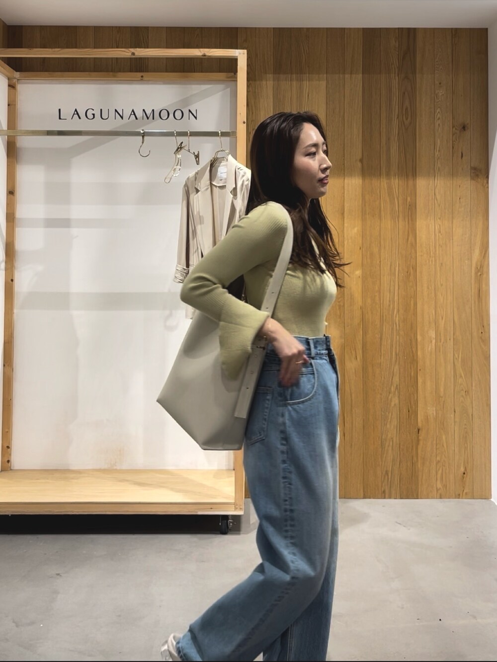 グリーン系のニット/セーター、ホワイト系のパンプス、ブルー系のデニムパンツを着用したレディースの冬コーディネートの2枚目の写真