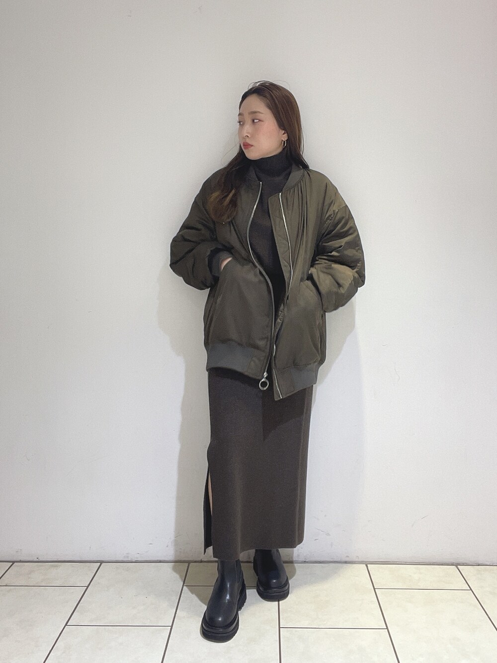 ブラウン系のニット/セーター、ブラウン系のスカート、ブラック系のブーツを着用したレディースの冬コーディネートの9枚目の写真