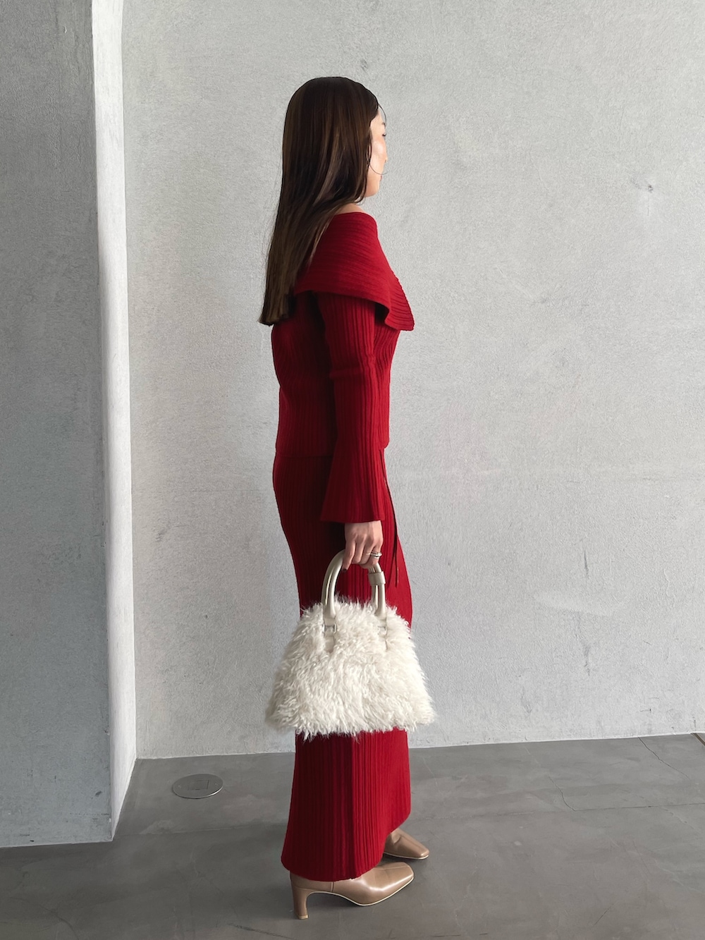 レッド系のニット/セーター、ベージュ系のブーツ、レッド系のスカートを着用したレディースの秋コーディネートの6枚目の写真