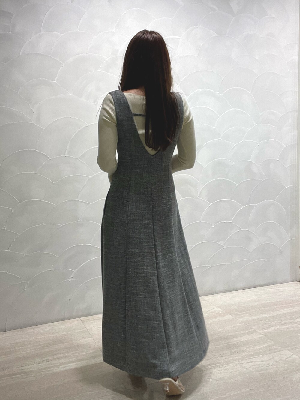 ホワイト系のサンダル、ホワイト系のニット/セーター、グレー系のジャンパースカートを着用したレディースの春コーディネートの4枚目の写真