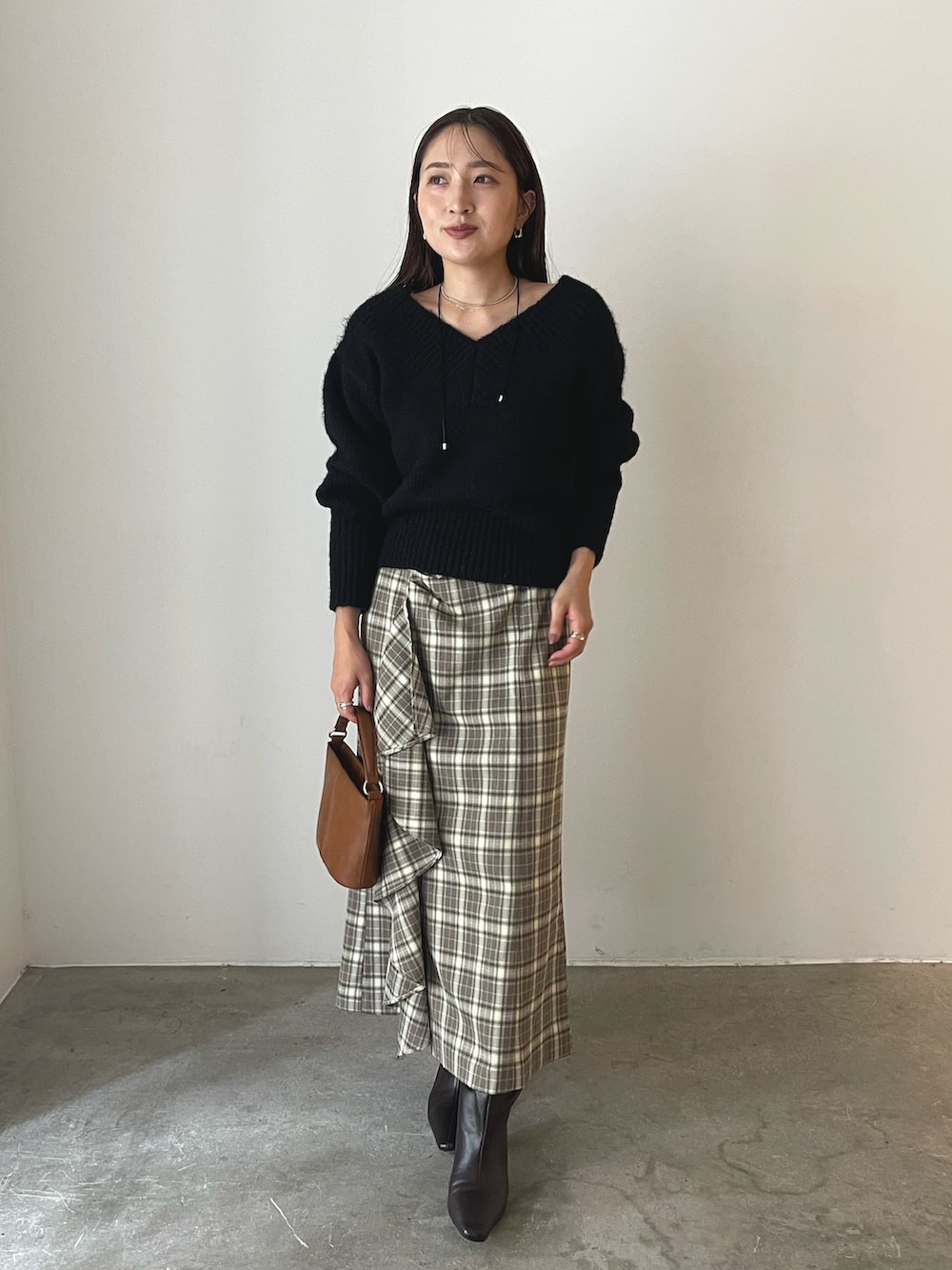 イエロー系のハンドバッグ、ブラウン系のブーツ、ブラウン系のスカートを着用したレディースの秋コーディネートの2枚目の写真