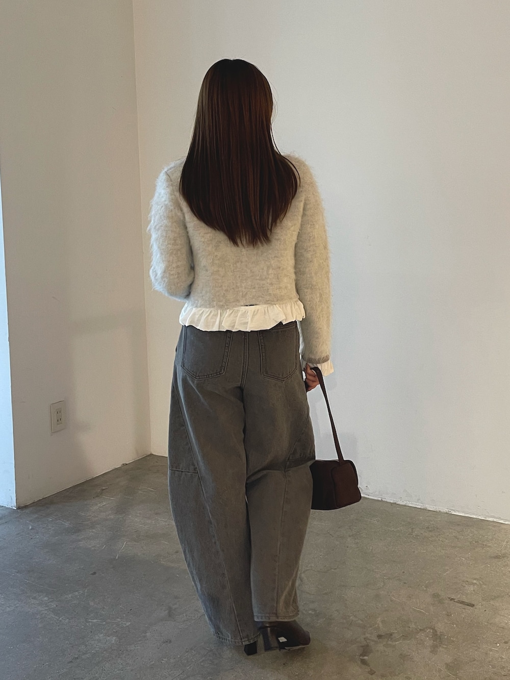 ブラウン系のハンドバッグ、グレー系のデニムパンツ、グレー系のノーカラージャケットを着用したレディースの秋コーディネートの5枚目の写真