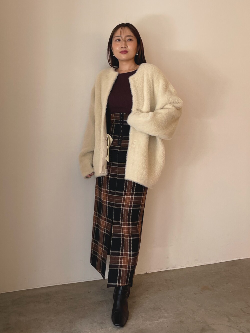 ブラウン系のニット/セーター、ブラウン系のスカート、ブラック系のブーツを着用したレディースの秋コーディネートの3枚目の写真