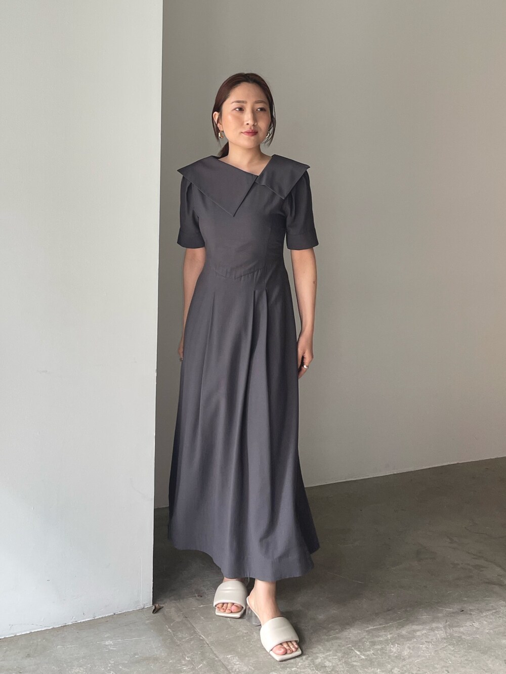 ホワイト系のサンダル、グレー系のワンピース、ゴールド系のピアス（両耳用）を着用したレディースの春コーディネートの2枚目の写真