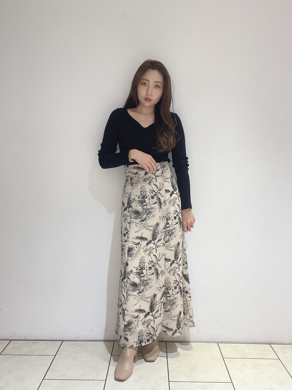 ベージュ系のスカート、ブラック系のニット/セーターを着用したレディースの秋コーディネートの6枚目の写真