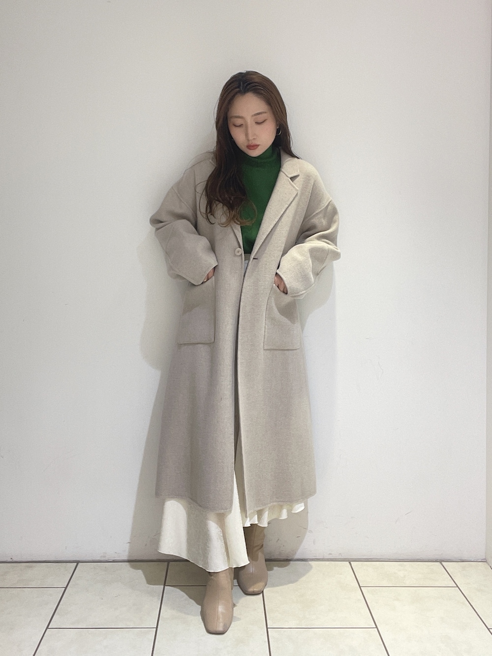 ホワイト系のスカート、ベージュ系のその他アウター、グリーン系のニット/セーターを着用したレディースの冬コーディネートの3枚目の写真