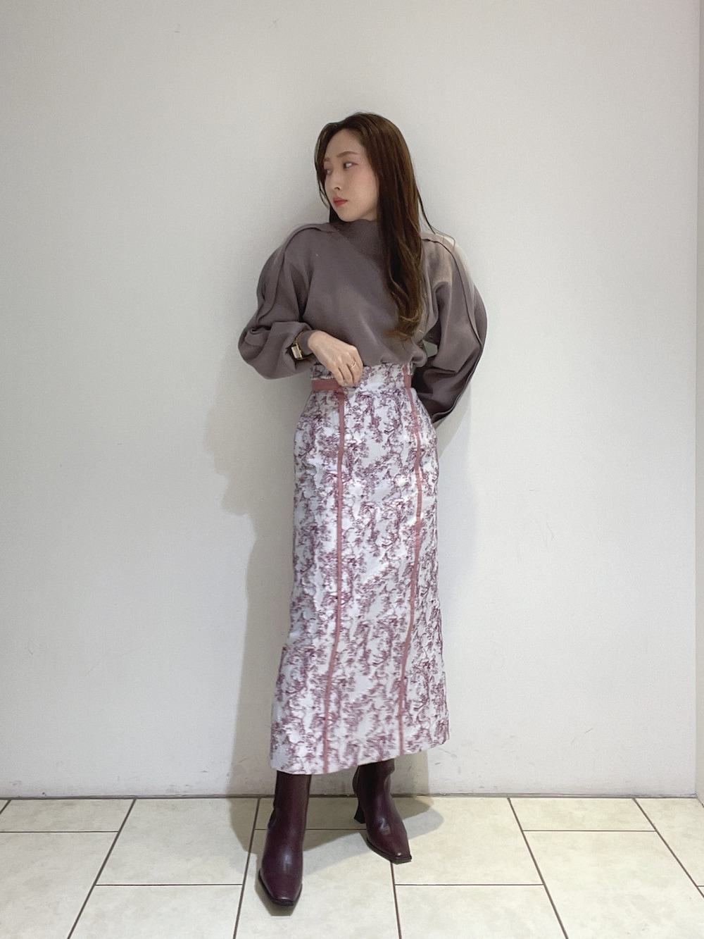 ピンク系のスカート、ブラウン系のニット/セーター、レッド系のブーツを着用したレディースの冬コーディネートの3枚目の写真