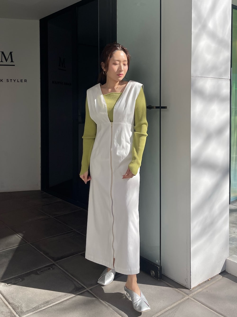 シルバー系のパンプス、グリーン系のニット/セーター、ホワイト系のジャンパースカートを着用したレディースの冬コーディネートの3枚目の写真