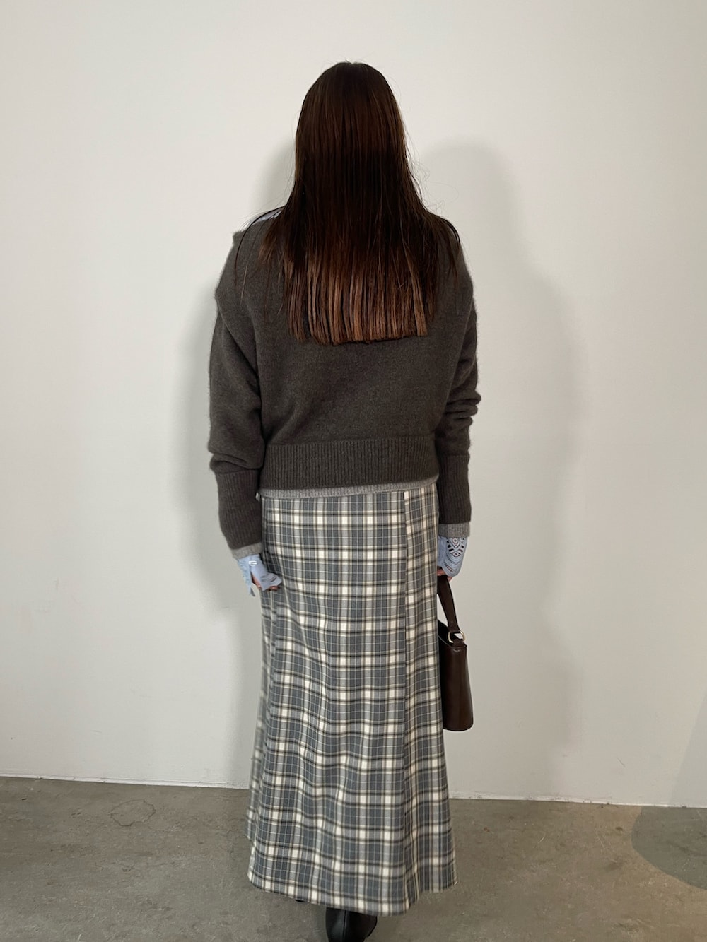 グレー系のスカート、ブラック系のブーツ、ブラウン系のハンドバッグを着用したレディースの秋コーディネートの6枚目の写真