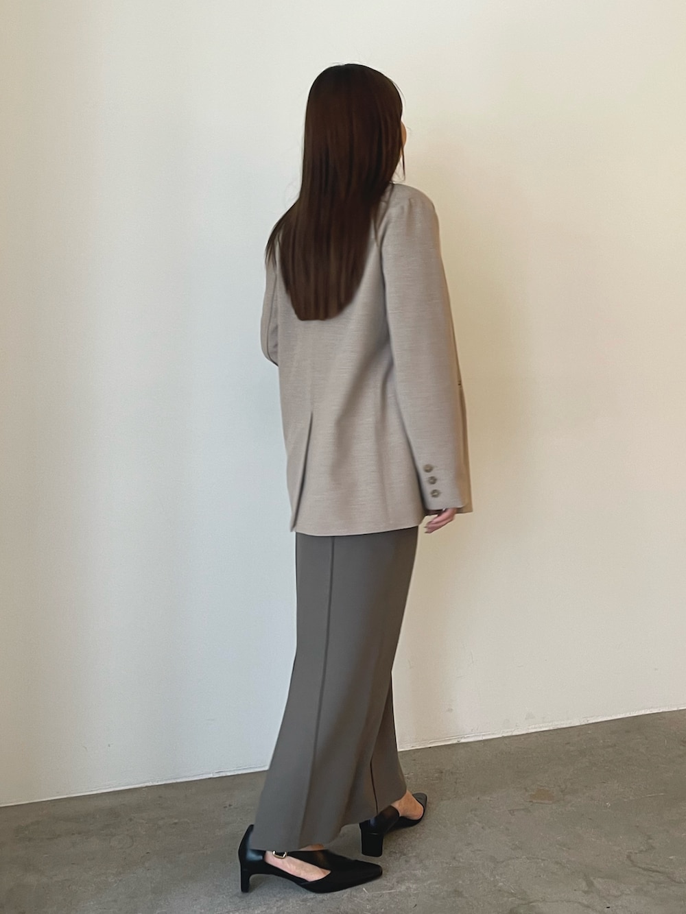 ブラック系のパンプス、グレー系のスカート、ベージュ系のニット/セーターを着用したレディースの秋コーディネートの4枚目の写真