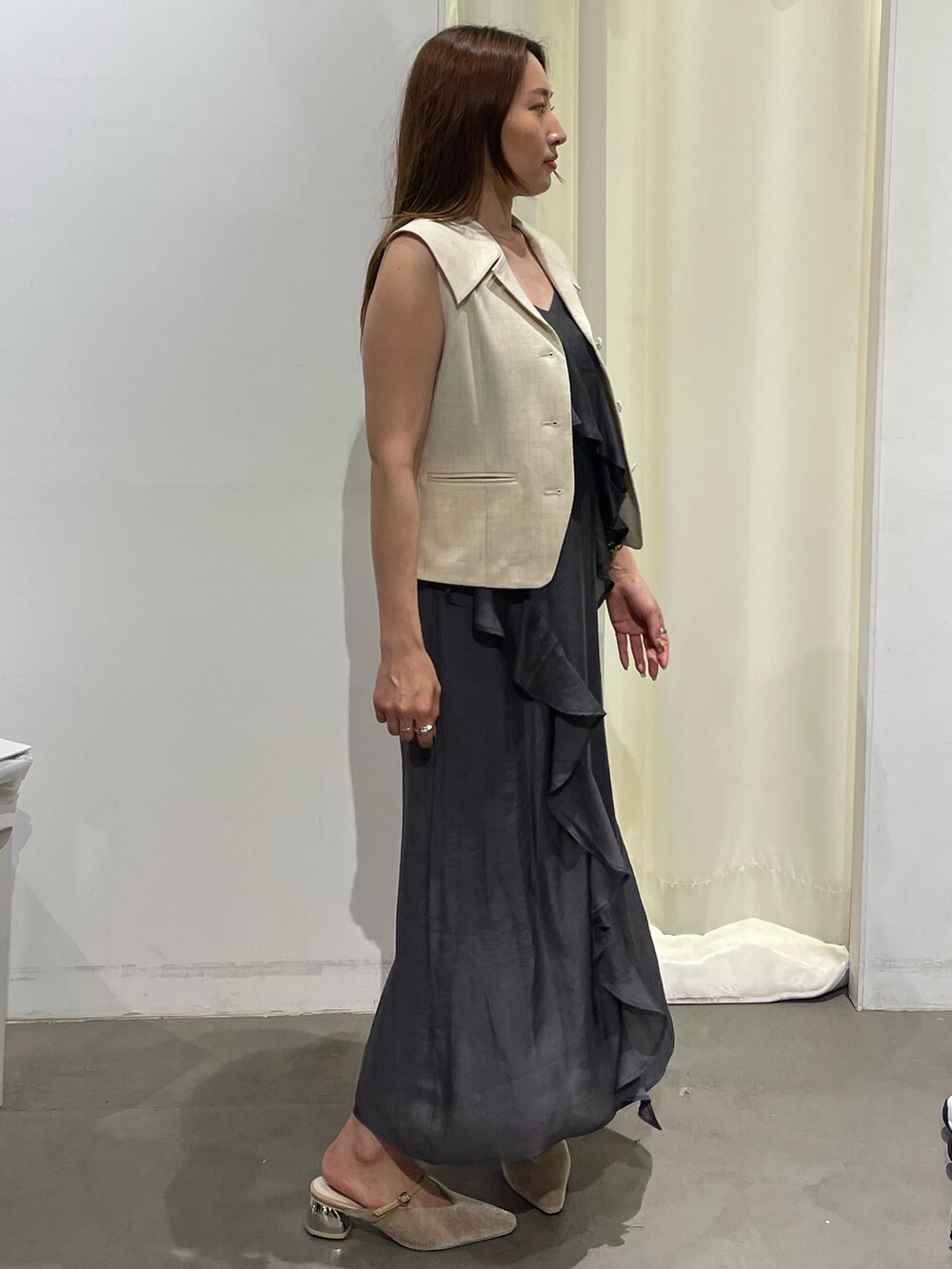 ホワイト系のベスト、グレー系のワンピース、ベージュ系のパンプスを着用したレディースの夏コーディネートの6枚目の写真