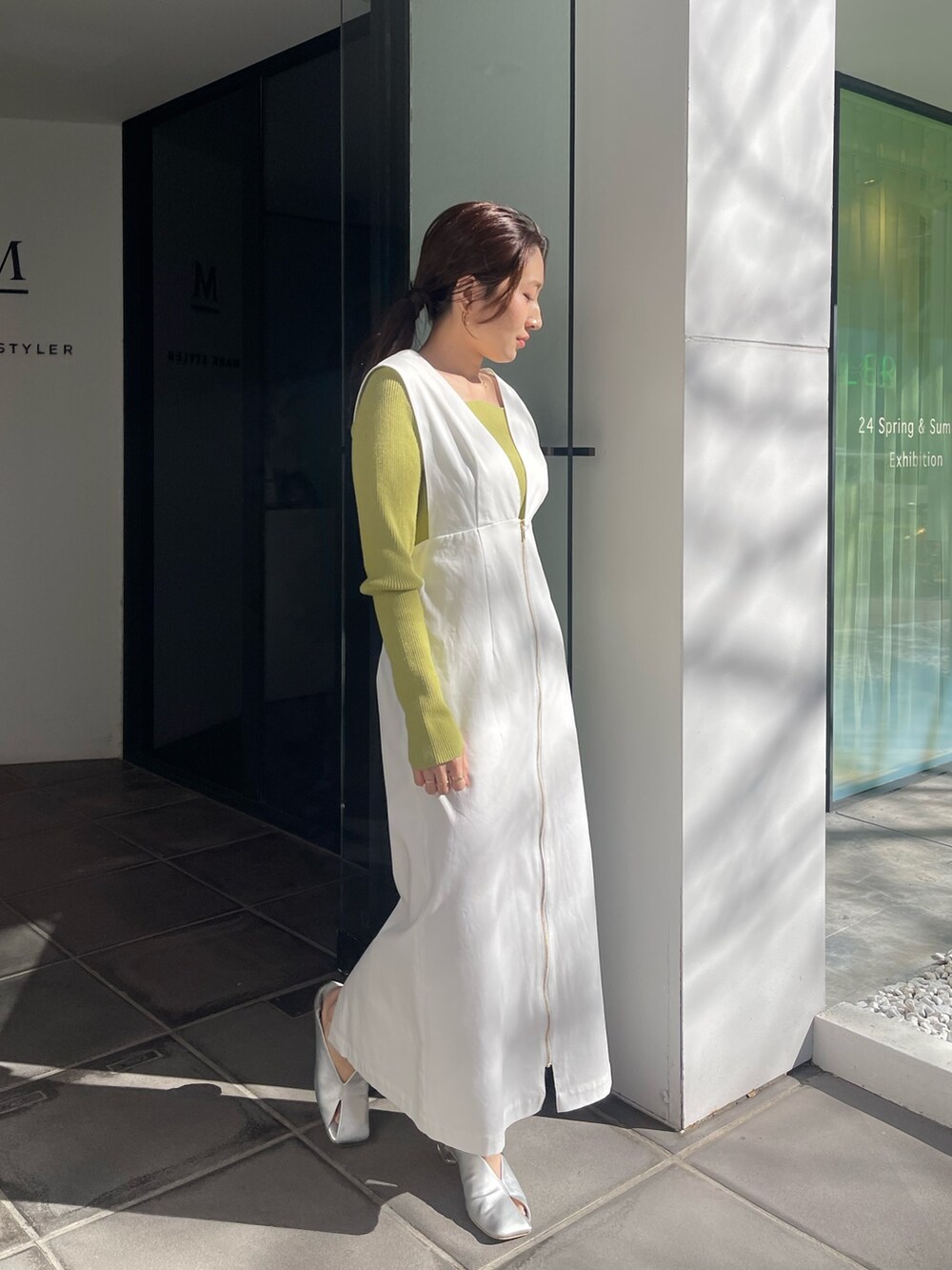 シルバー系のパンプス、グリーン系のニット/セーター、ホワイト系のジャンパースカートを着用したレディースの冬コーディネートの2枚目の写真