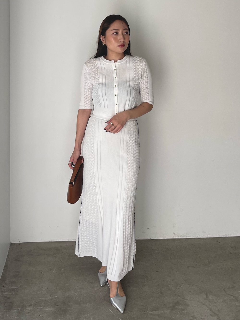 イエロー系のハンドバッグ、シルバー系のパンプス、ホワイト系のワンピースを着用したレディースの冬コーディネートの4枚目の写真