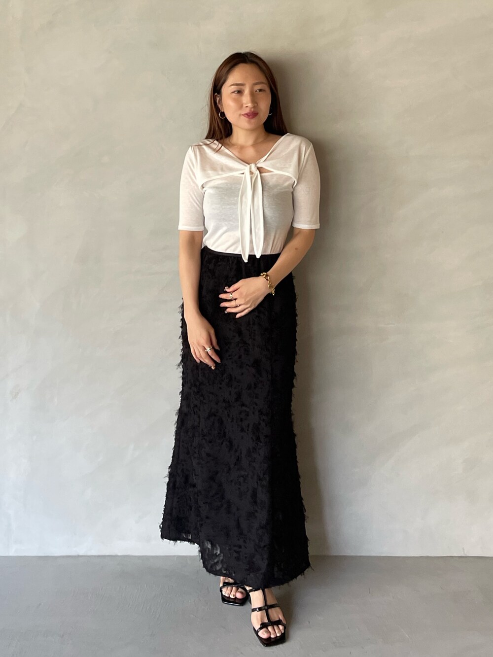 ブラック系のサンダル、ブラック系のスカート、ホワイト系のTシャツ/カットソーを着用したレディースの夏コーディネートの2枚目の写真