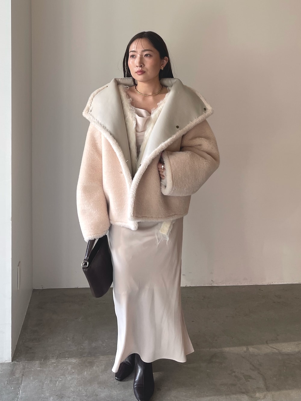 ベージュ系のワンピース、ブラウン系のハンドバッグ、ブラウン系のブーツを着用したレディースの冬コーディネートの8枚目の写真