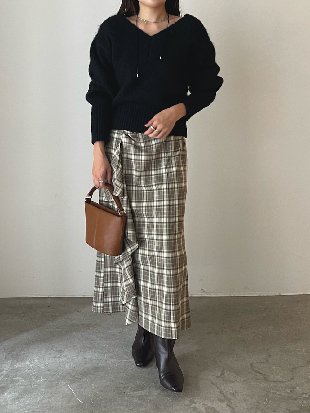 イエロー系のハンドバッグ、ブラウン系のブーツ、ブラウン系のスカートを着用したレディースの秋コーディネートの7枚目の写真