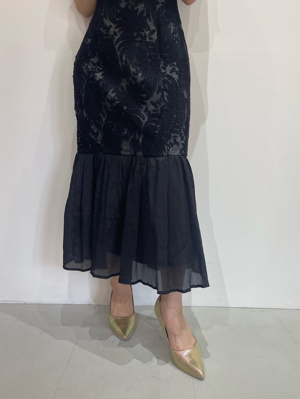 ブラック系のドレス、ゴールド系のパンプス、ゴールド系のピアス（両耳用）を着用したレディースの秋コーディネートの8枚目の写真