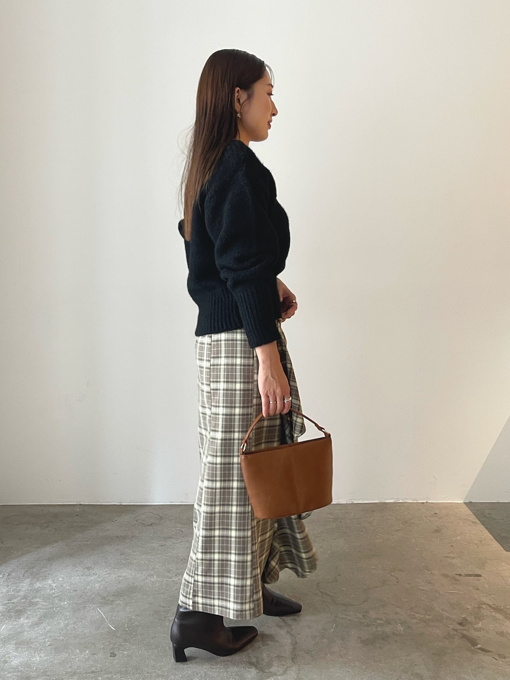 イエロー系のハンドバッグ、ブラウン系のブーツ、ブラウン系のスカートを着用したレディースの秋コーディネートの5枚目の写真