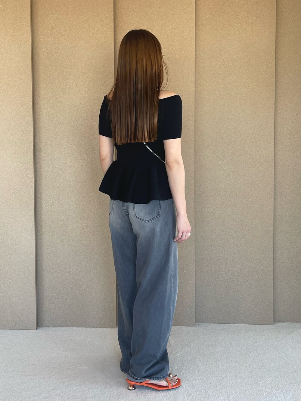 ブラック系のニット/セーター、グレー系のデニムパンツ、オレンジ系のサンダルを着用したレディースの春コーディネートの5枚目の写真