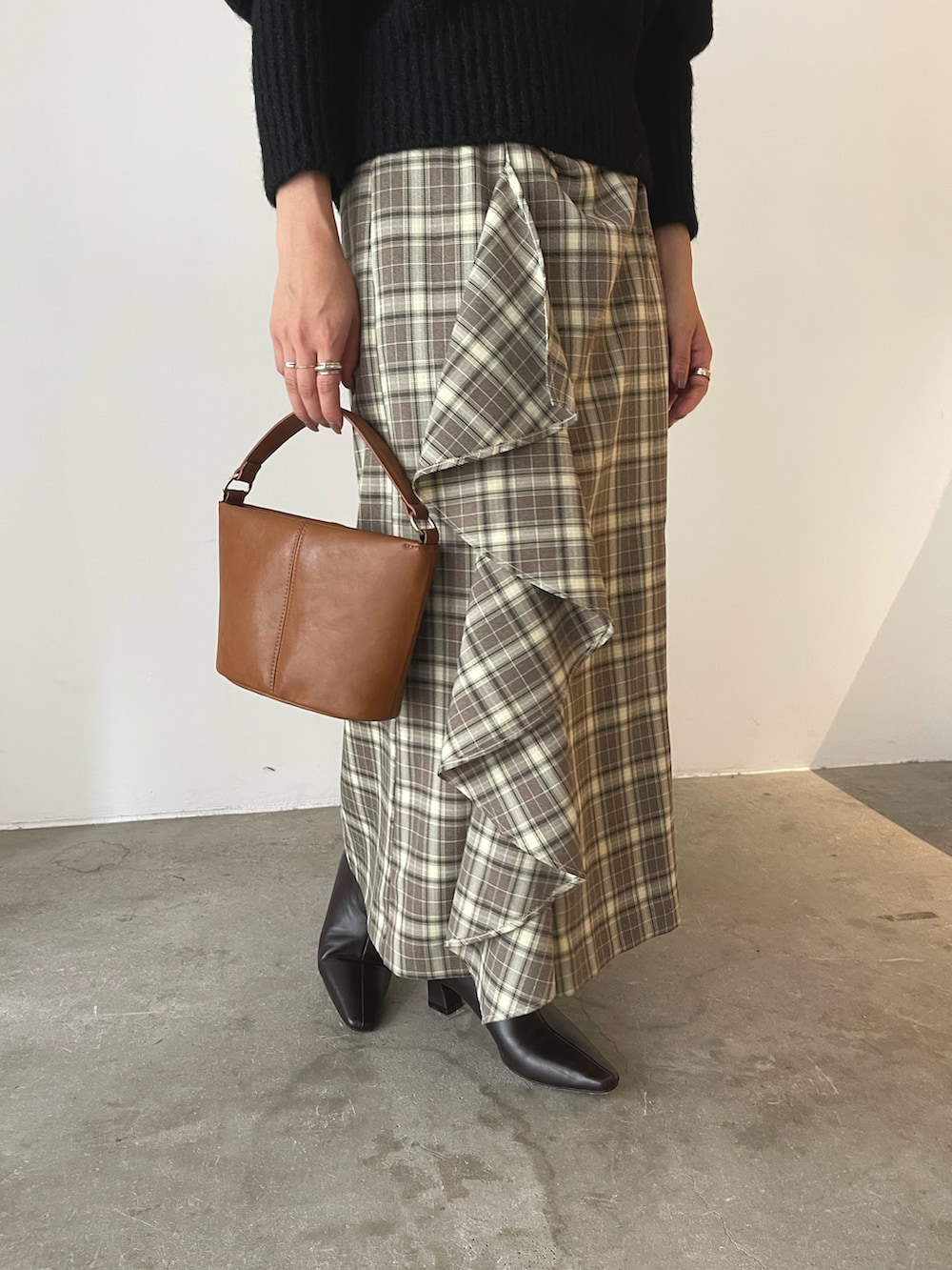 イエロー系のハンドバッグ、ブラウン系のブーツ、ブラウン系のスカートを着用したレディースの秋コーディネートの8枚目の写真