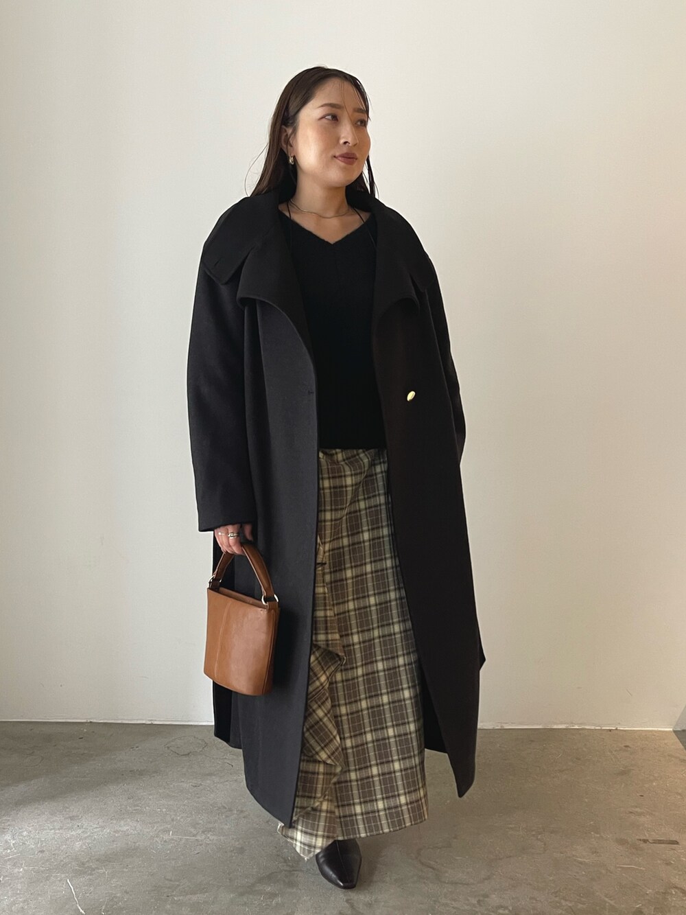 ブラウン系のスカート、イエロー系のハンドバッグ、グレー系のチェスターコートを着用したレディースの秋コーディネートの4枚目の写真