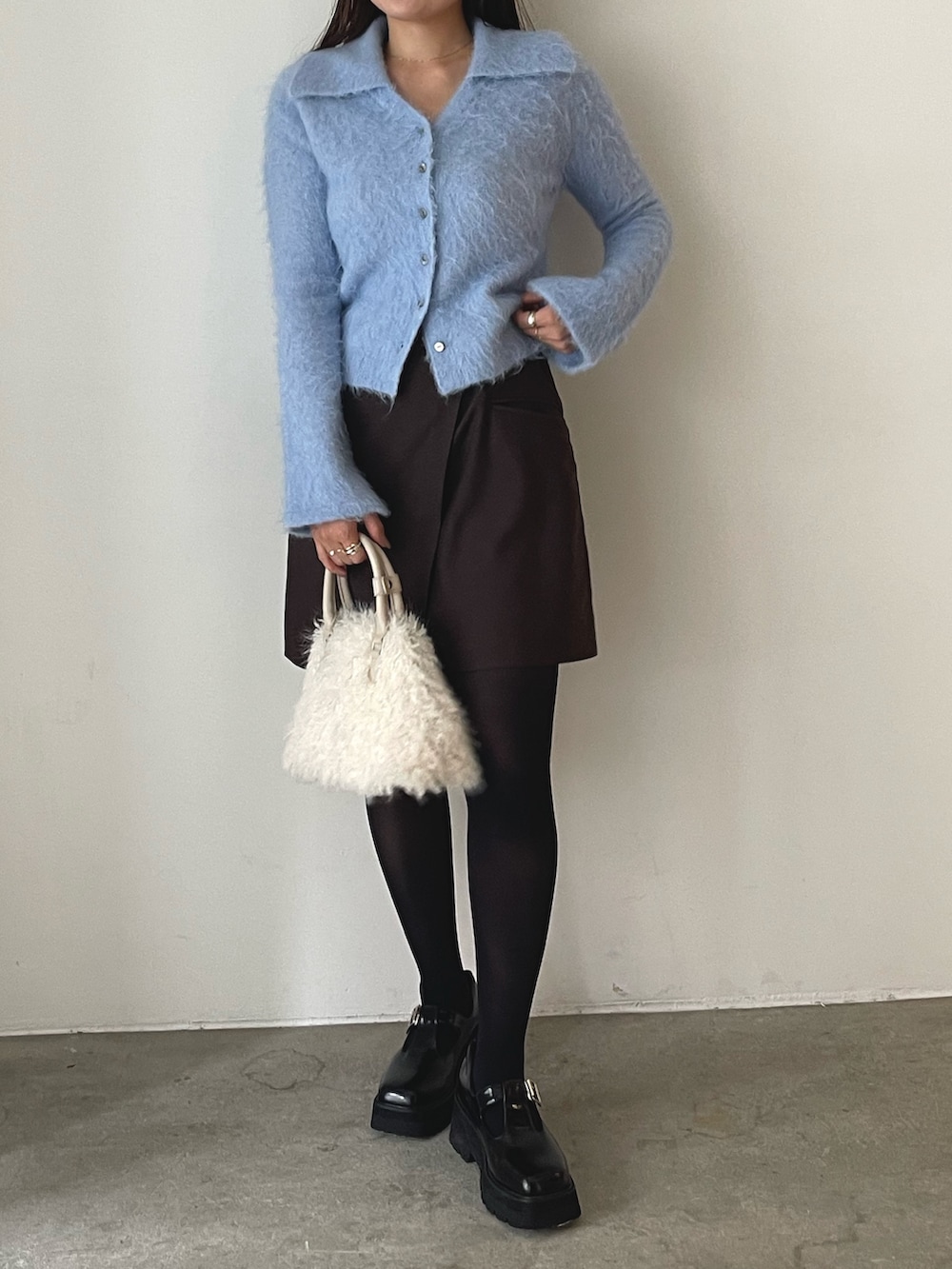 ホワイト系のボストンバッグ、ブラウン系のスカート、ブラック系のローファーを着用したレディースの秋コーディネートの3枚目の写真