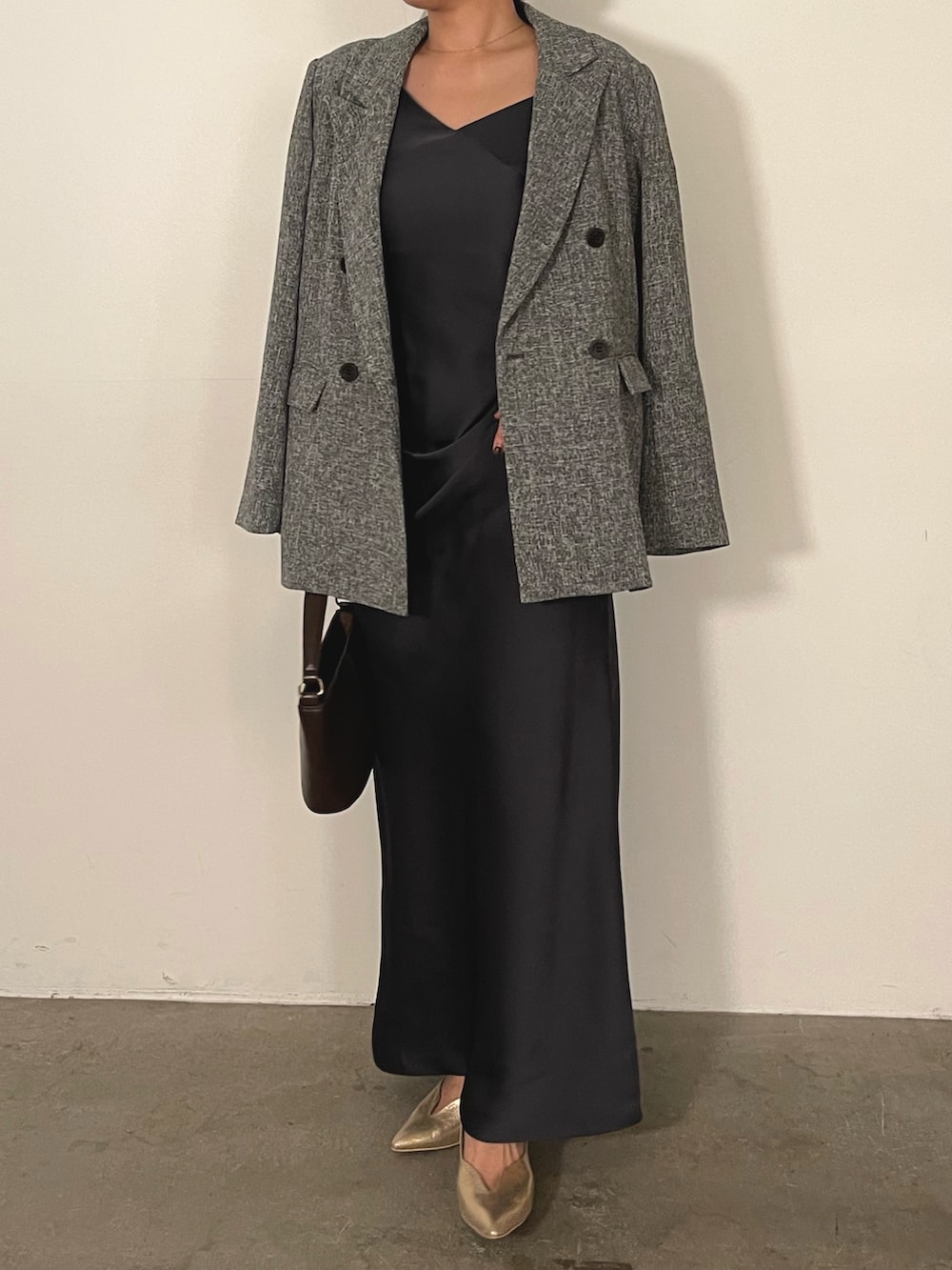 グレー系のドレス、ブラウン系のハンドバッグ、ゴールド系のパンプスを着用したレディースの冬コーディネートの3枚目の写真