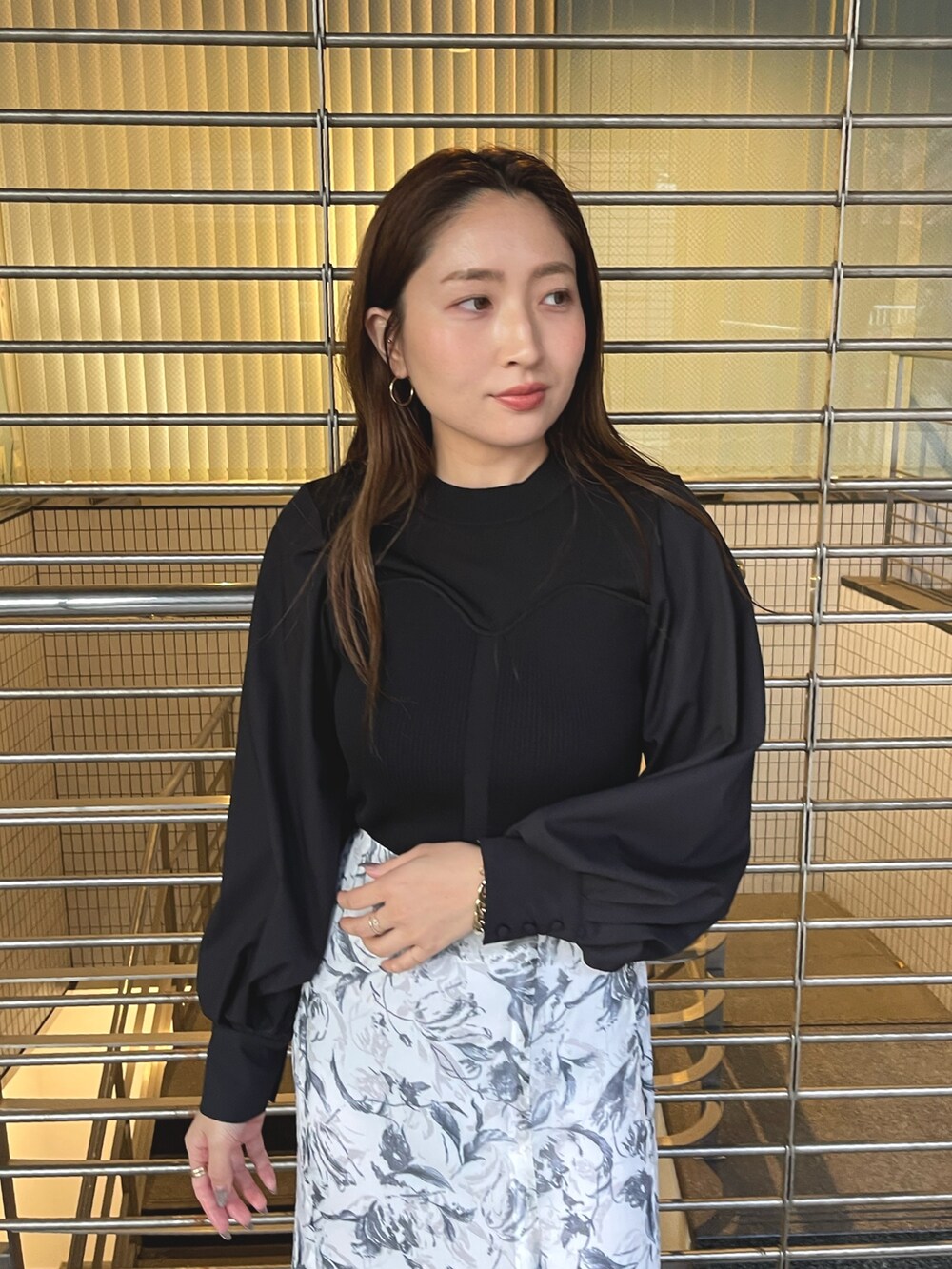 グレー系のスカート、シルバー系のパンプス、ブラック系のニット/セーターを着用したレディースの冬コーディネートの7枚目の写真