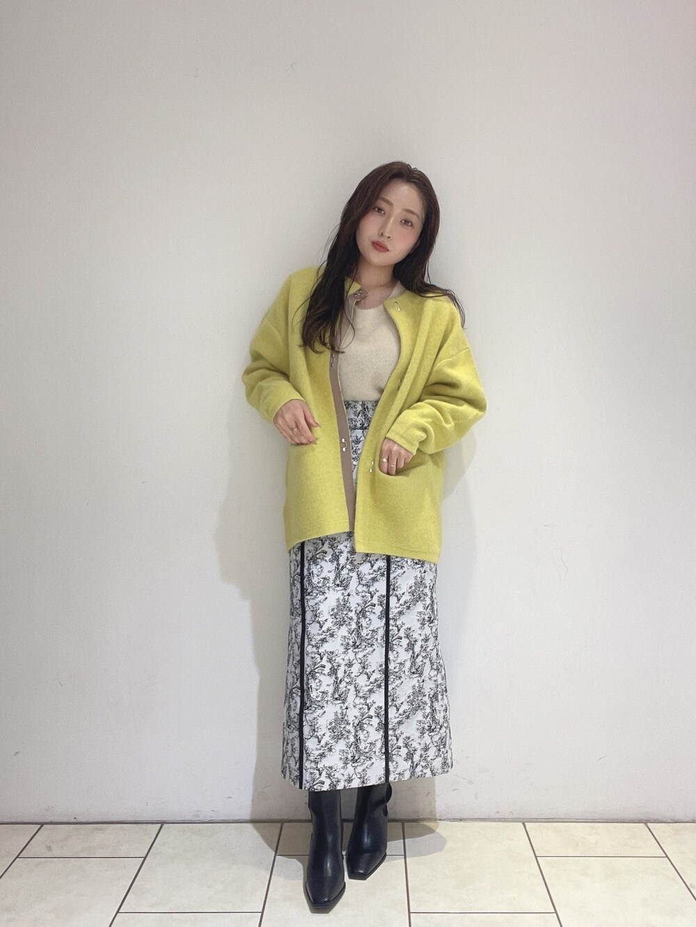 イエロー系のカーディガン/ボレロ、ブラック系のスカート、ホワイト系のニット/セーターを着用したレディースの秋コーディネートの6枚目の写真