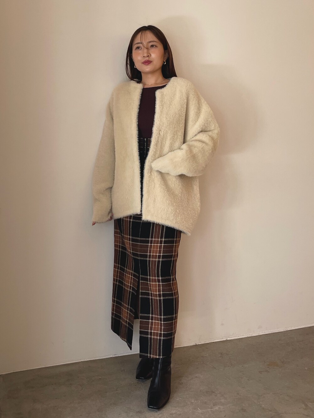 ブラウン系のニット/セーター、ブラウン系のスカート、ブラック系のブーツを着用したレディースの秋コーディネートの2枚目の写真