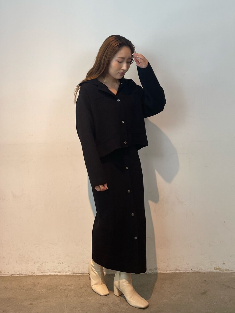 ブラック系のカーディガン/ボレロ、ブラック系のスカート、ホワイト系のブーツを着用したレディースの夏コーディネートの2枚目の写真