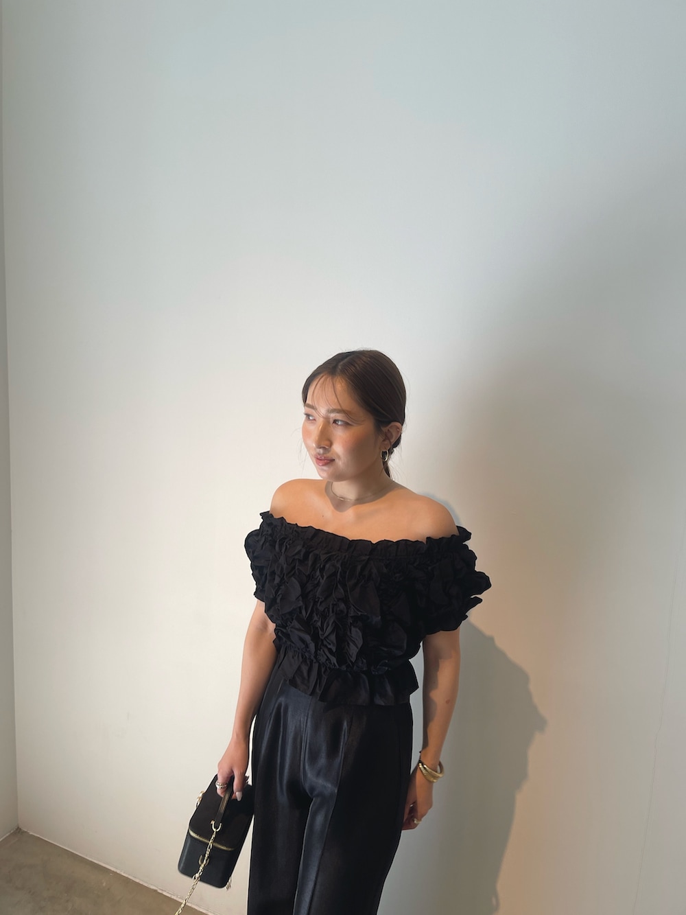 ブラック系のハンドバッグ、ゴールド系のパンプス、ブラック系のパンツドレスを着用したレディースの春コーディネートの8枚目の写真