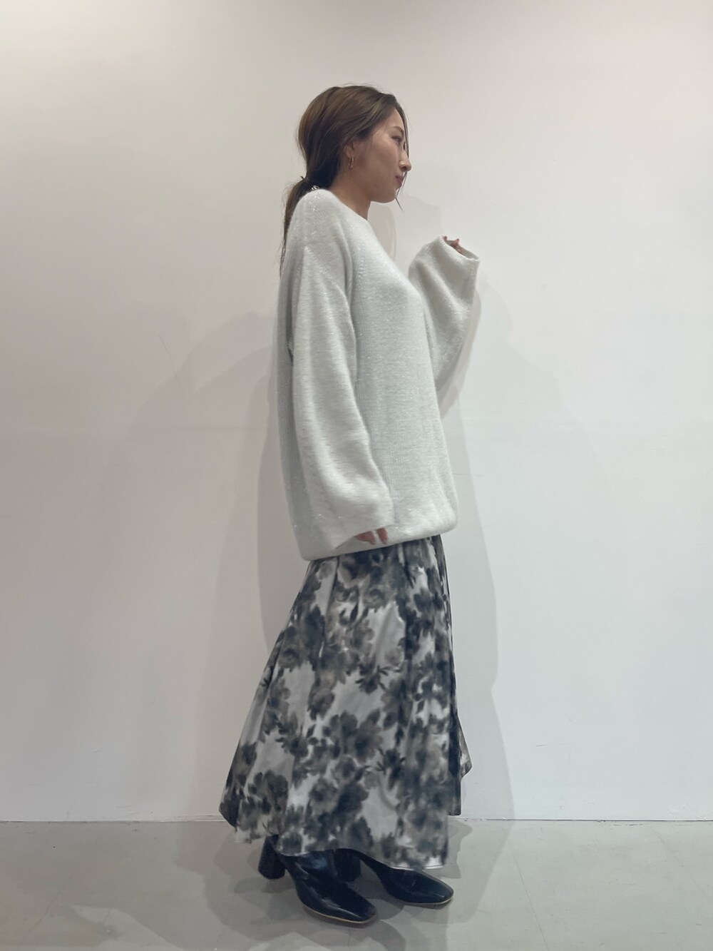 ブラック系のスカート、ブラック系のブーツ、ホワイト系のニット/セーターを着用したレディースの夏コーディネートの3枚目の写真