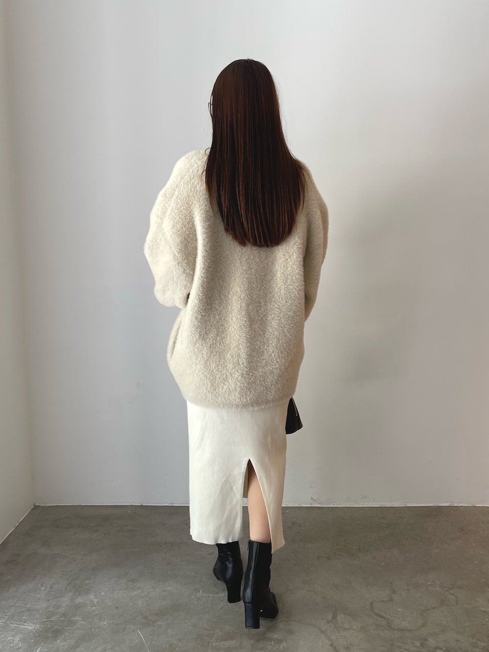 ブラウン系のボストンバッグ、ブラック系のブーツ、ホワイト系のワンピースを着用したレディースの秋コーディネートの7枚目の写真