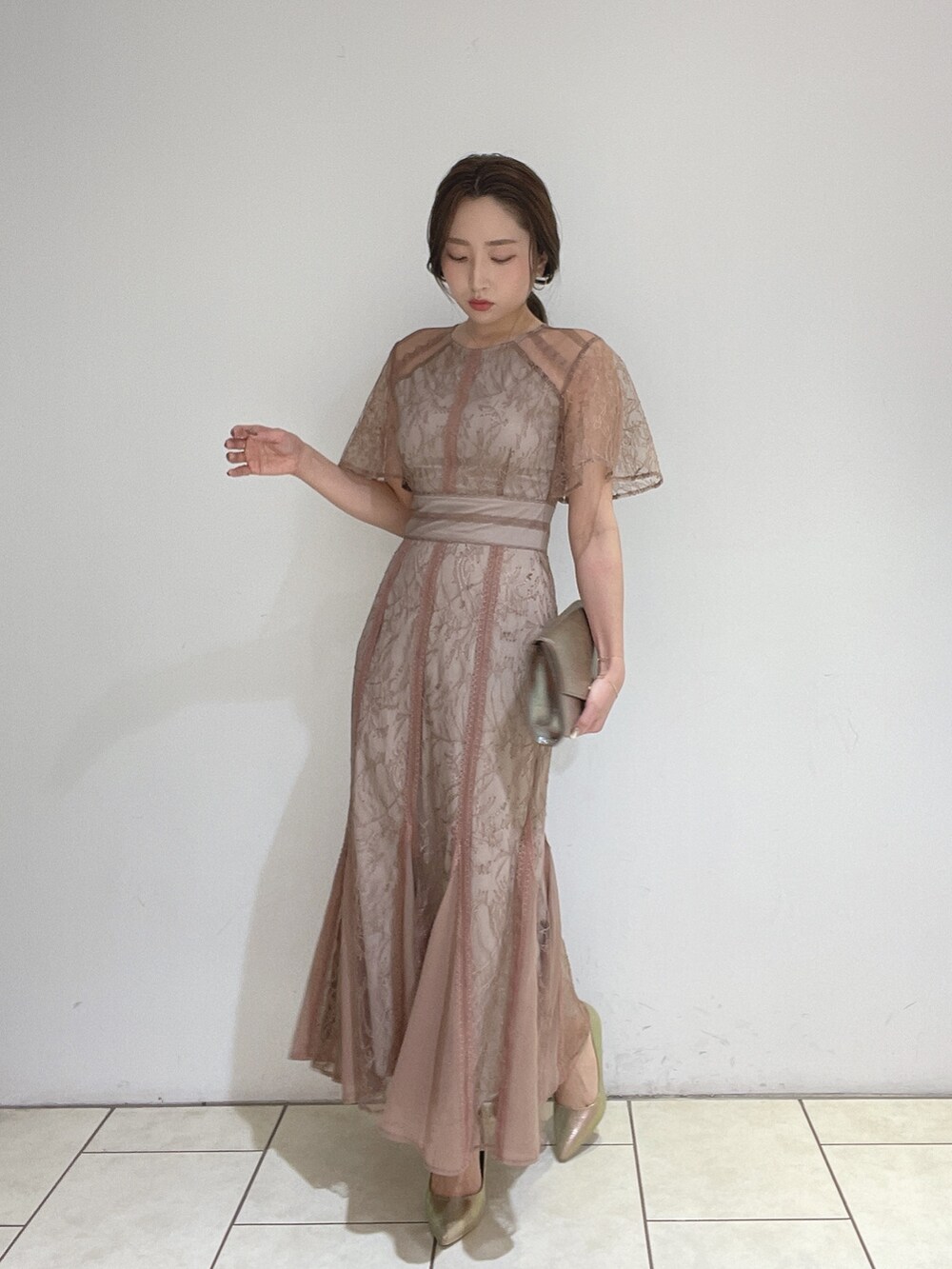 ブラウン系のドレス、ゴールド系のパンプス、ゴールド系のハンドバッグを着用したレディースの冬コーディネートの7枚目の写真