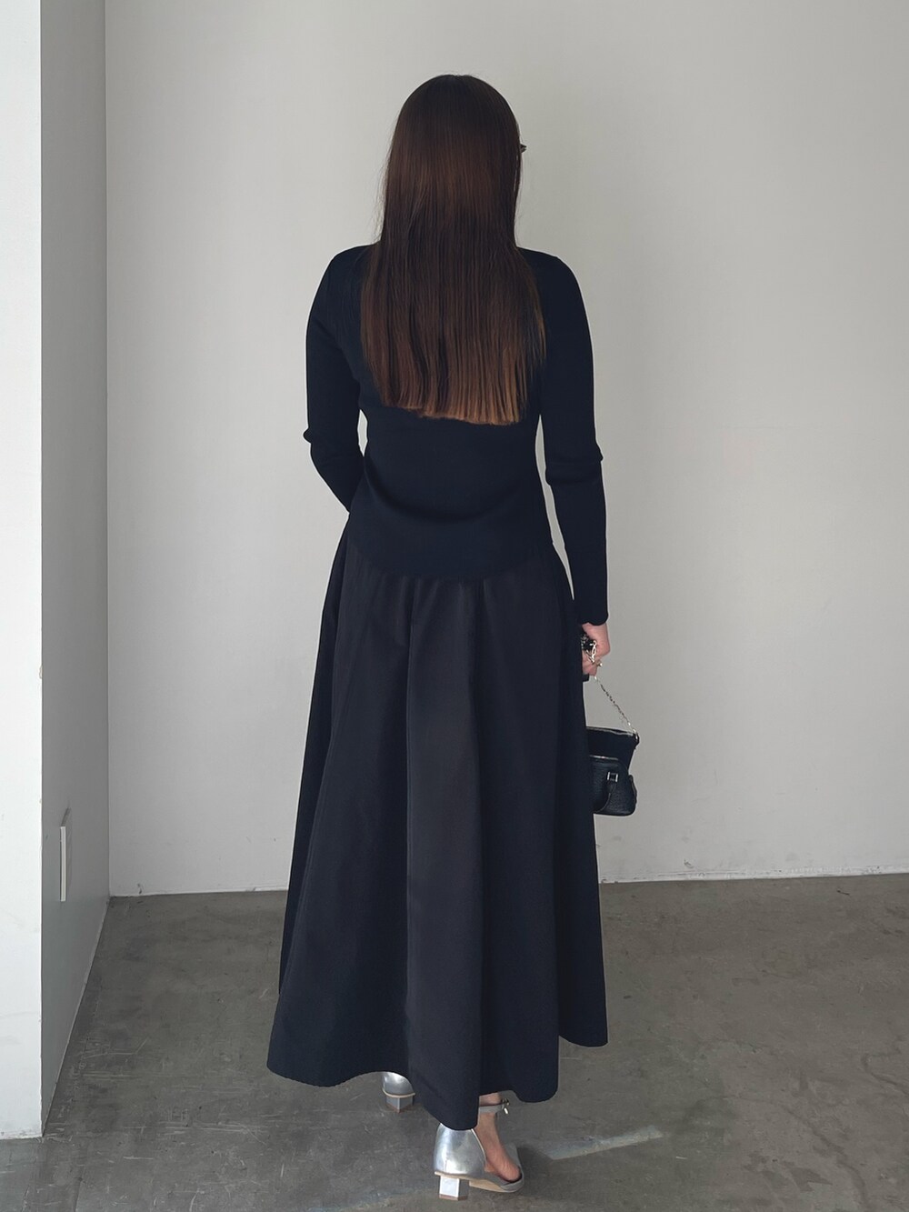 シルバー系のパンプス、ブラック系のワンピース、ゴールド系のピアス（両耳用）を着用したレディースの冬コーディネートの7枚目の写真