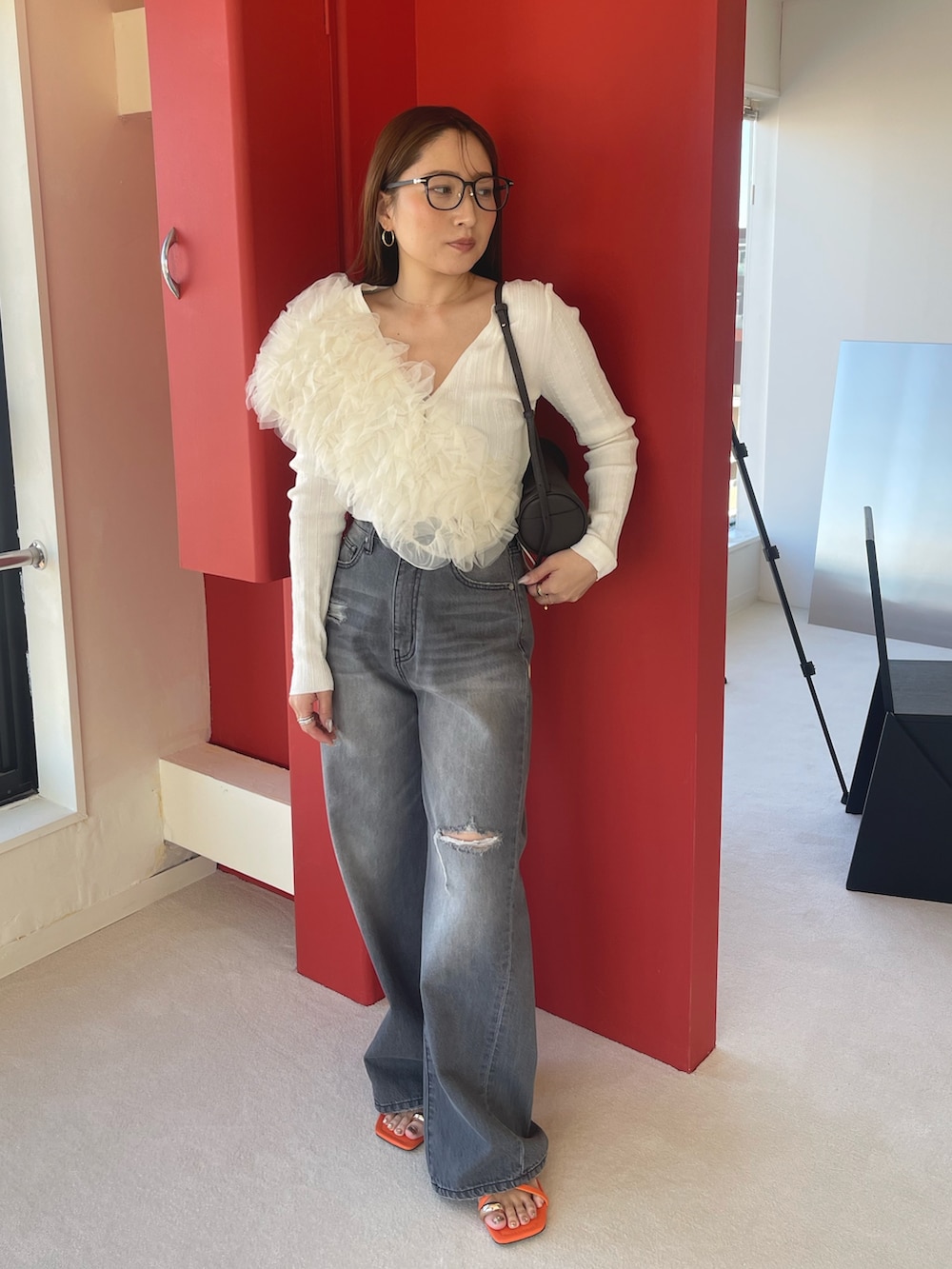 オレンジ系のサンダル、グレー系のデニムパンツ、ホワイト系のカーディガン/ボレロを着用したレディースの春コーディネートの6枚目の写真