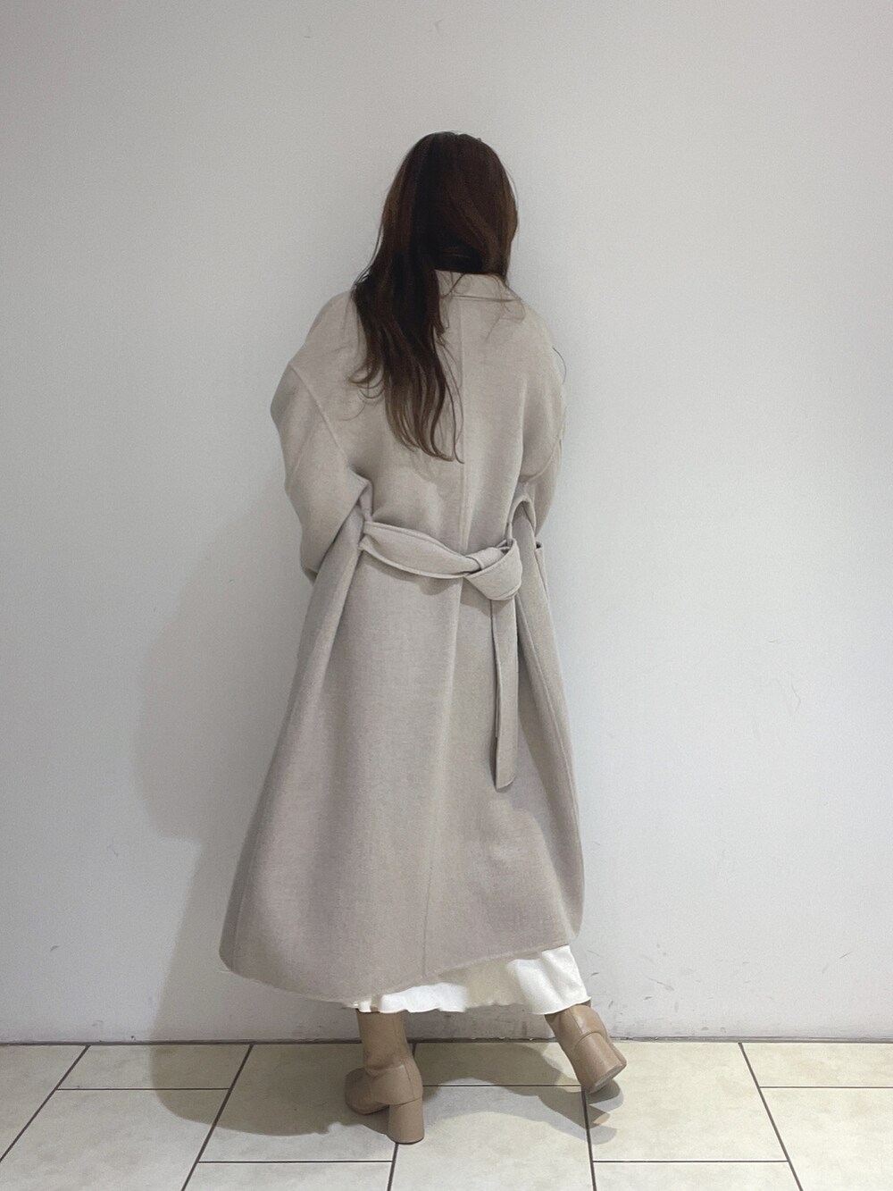 ホワイト系のスカート、ベージュ系のその他アウター、グリーン系のニット/セーターを着用したレディースの冬コーディネートの7枚目の写真