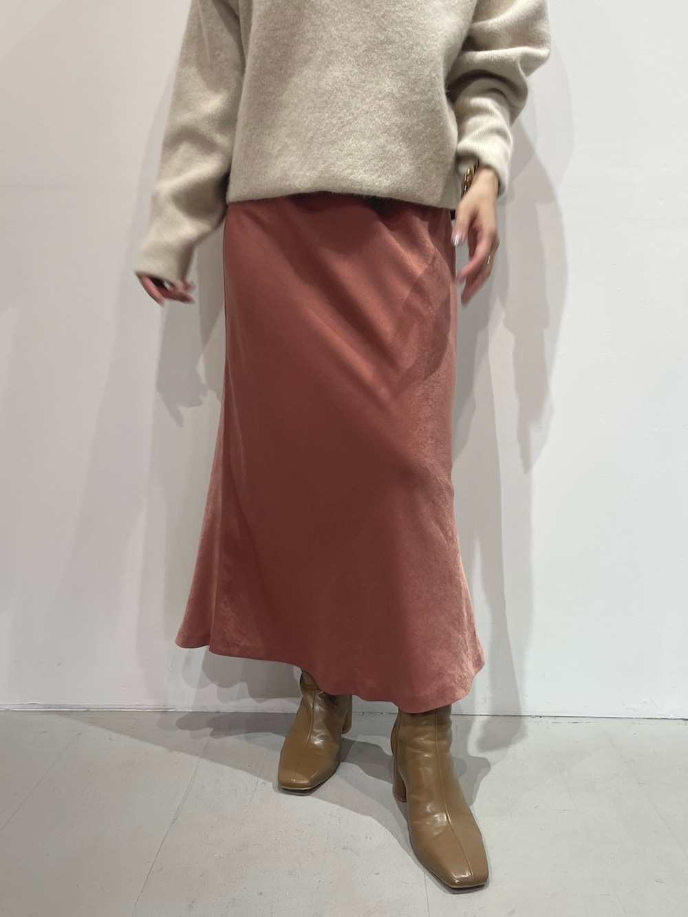 ピンク系のスカート、ベージュ系のブーツ、ホワイト系のパーカーを着用したレディースの夏コーディネートの5枚目の写真