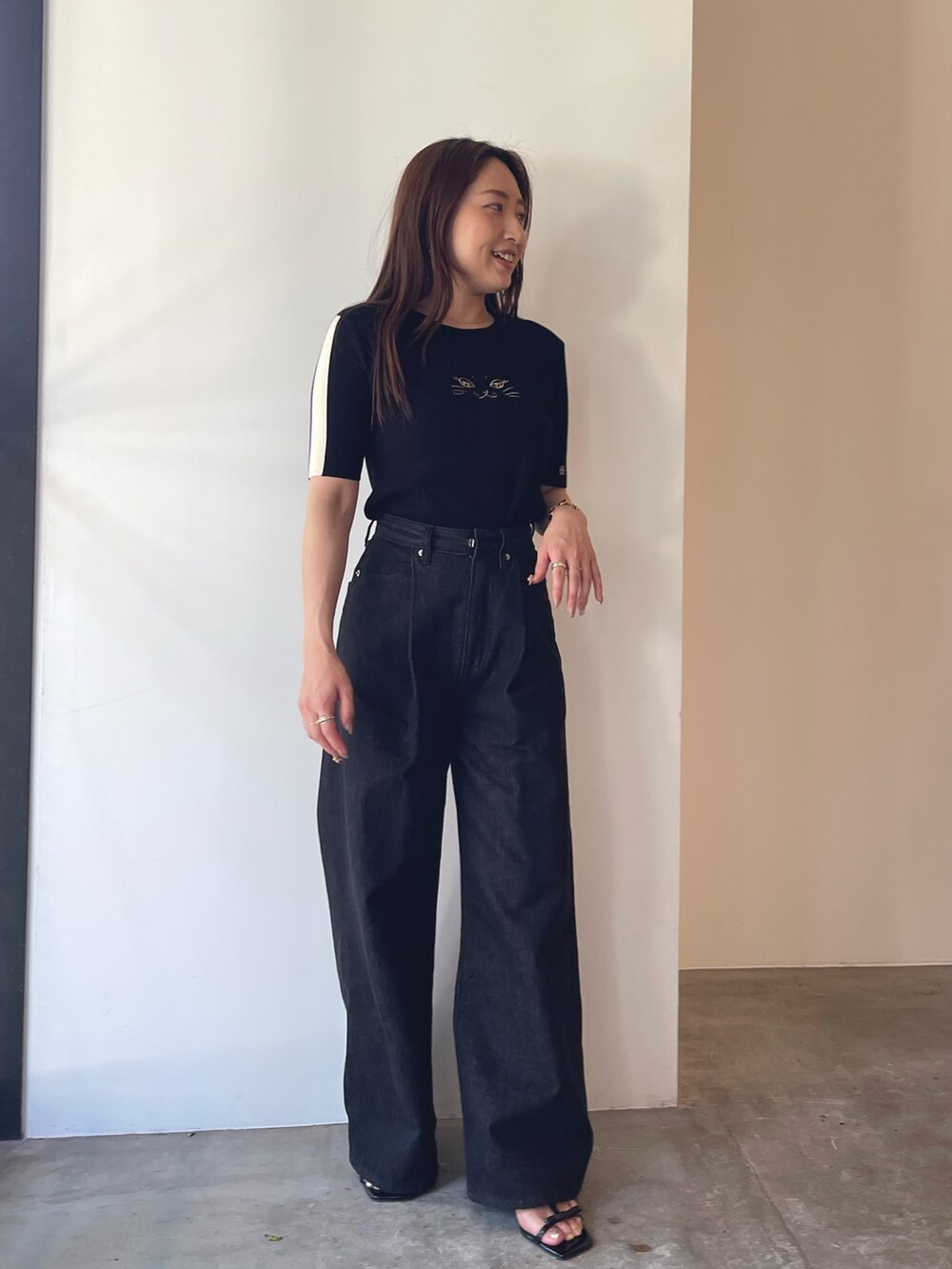 ブラック系のサンダル、ブラック系のニット/セーター、ブラック系のデニムパンツを着用したレディースの夏コーディネートの3枚目の写真