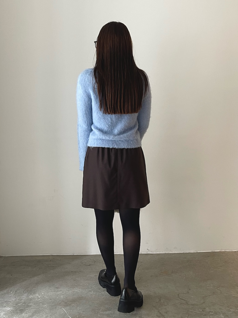 ホワイト系のボストンバッグ、ブラウン系のスカート、ブラック系のローファーを着用したレディースの秋コーディネートの5枚目の写真