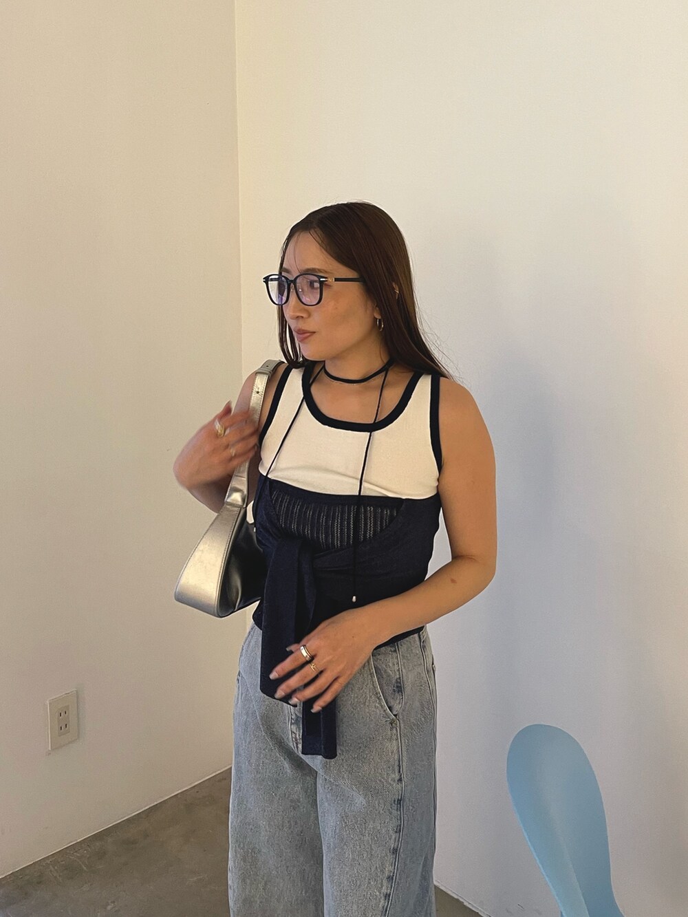 ブルー系のデニムパンツ、シルバー系のハンドバッグ、ブラウン系のサンダルを着用したレディースの春コーディネートの7枚目の写真