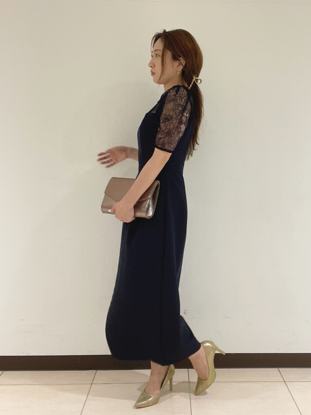 ブルー系のドレス、ゴールド系のハンドバッグ、ゴールド系のパンプスを着用したレディースの夏コーディネートの6枚目の写真